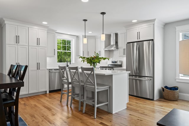 15 Adena Way, Kennebunk, ME 04043 - kitchen with wall chimney exhaust hood, appliances with stainless steel finishes, a center island, light countertops, and light wood-style flooring