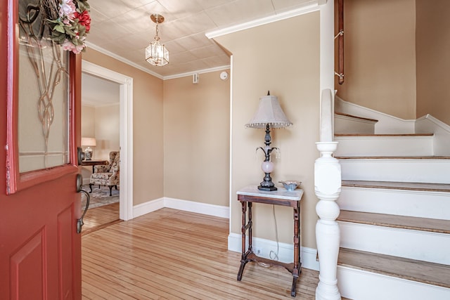 entrance foyer featuring light wood-style flooring, a chandelier, stairs, crown molding, and baseboards