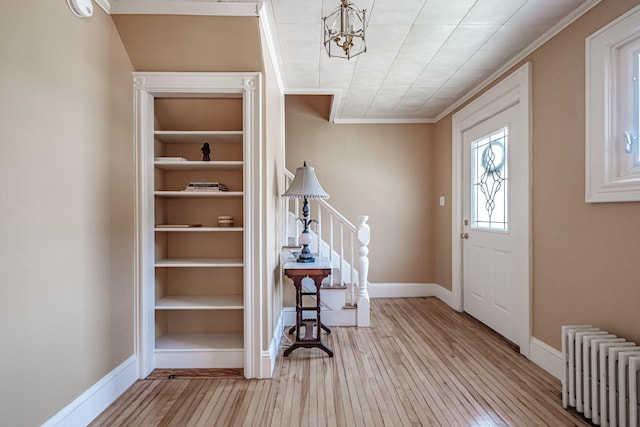 foyer entrance with radiator, ornamental molding, hardwood / wood-style floors, baseboards, and a chandelier