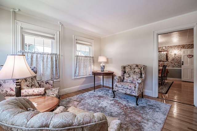living area with baseboards, crown molding, wood finished floors, and wallpapered walls