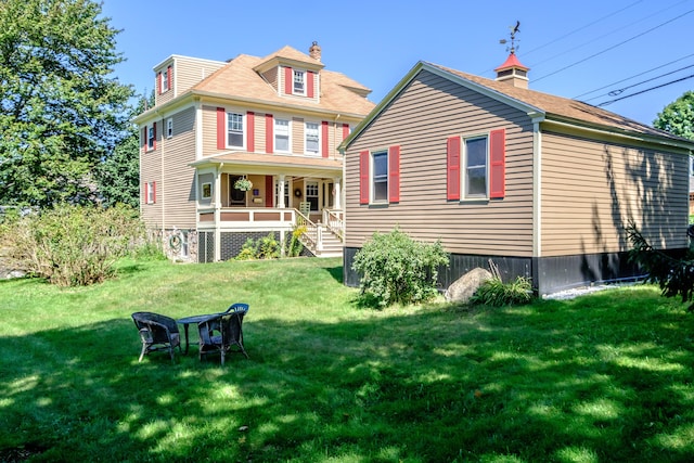 rear view of property featuring covered porch and a yard