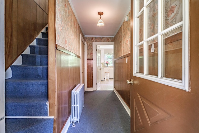 corridor featuring radiator, wallpapered walls, carpet flooring, stairway, and crown molding