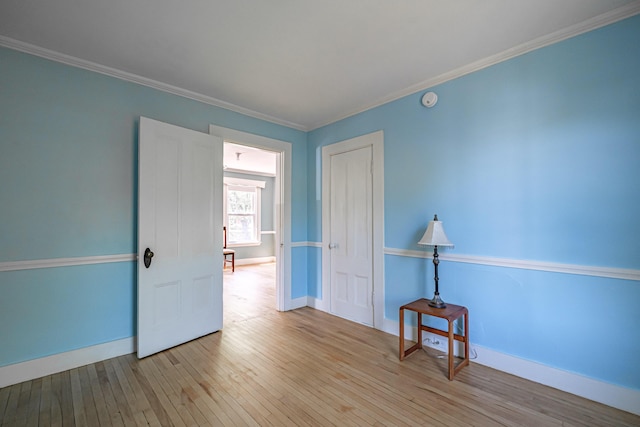 empty room with wood-type flooring, baseboards, ornamental molding, and a smoke detector