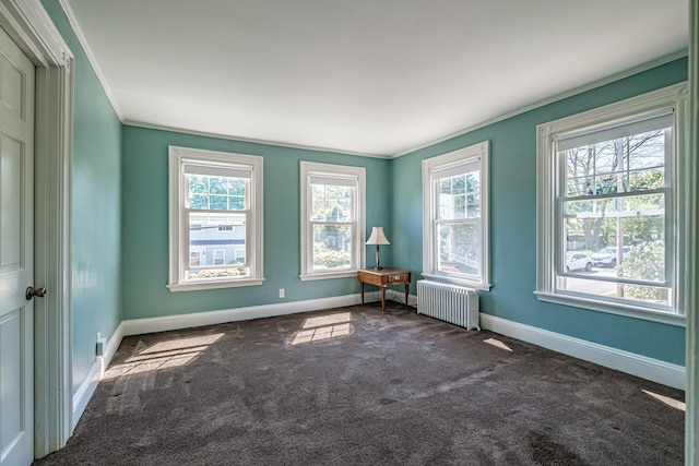 carpeted spare room featuring radiator, baseboards, and crown molding
