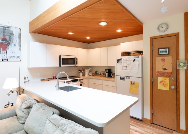 2396 Hemlock Dr Unit 2396, Carrabassett Valley, ME 04947 - kitchen featuring white appliances, a sink, a peninsula, light countertops, and decorative backsplash