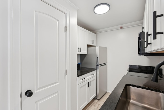 5 Kinney Ave Unit 303, Old Orchard Beach, ME 04064 - kitchen featuring dark countertops, a sink, freestanding refrigerator, light wood-style floors, and white cabinetry