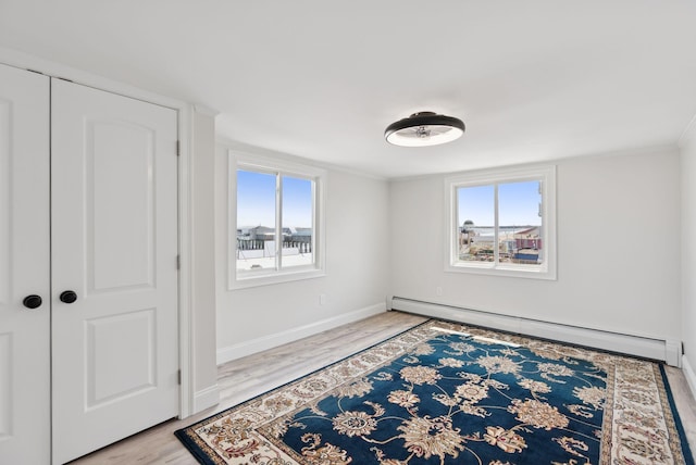 5 Kinney Ave Unit 303, Old Orchard Beach, ME 04064 - unfurnished bedroom with a baseboard heating unit, multiple windows, light wood-style flooring, baseboards, and ornamental molding