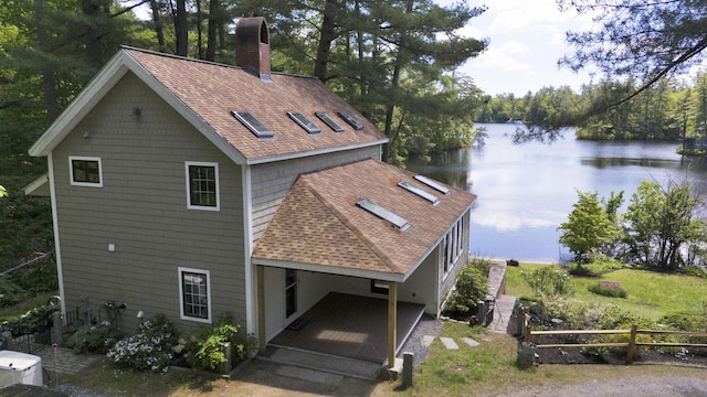 30 Otter Cove Ln, North Berwick, ME 03906 - back of property with a water view, a shingled roof, a chimney, and a forest view