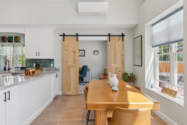 29 Bay Field Dr, Woolwich, ME 04579 - dining room with a wall unit AC, a barn door, and light wood-style flooring