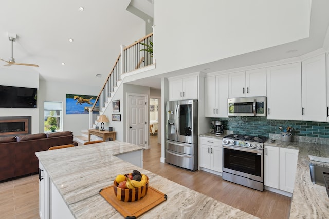 29 Bay Field Dr, Woolwich, ME 04579 - kitchen featuring appliances with stainless steel finishes, open floor plan, a ceiling fan, tasteful backsplash, and white cabinets