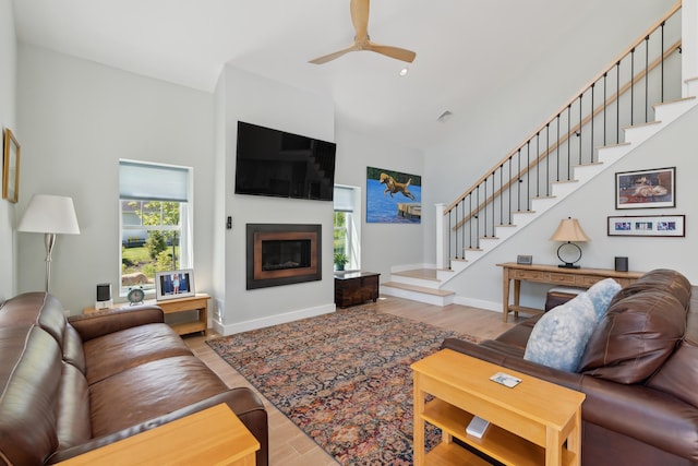 29 Bay Field Dr, Woolwich, ME 04579 - living room with high vaulted ceiling, stairs, wood finished floors, a ceiling fan, and a glass covered fireplace