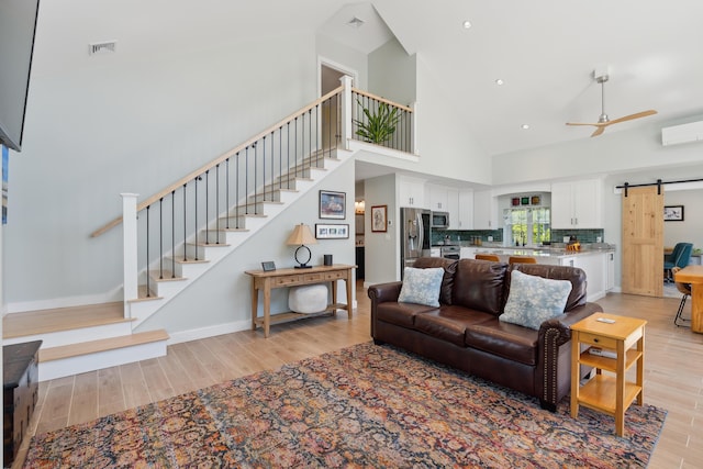 29 Bay Field Dr, Woolwich, ME 04579 - living area featuring a barn door, stairs, light wood finished floors, high vaulted ceiling, and ceiling fan