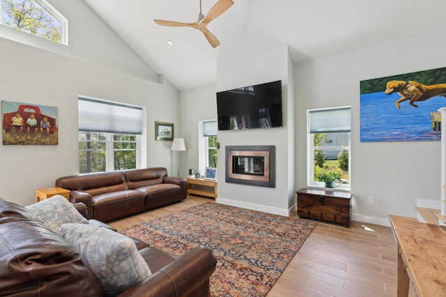 29 Bay Field Dr, Woolwich, ME 04579 - living room with high vaulted ceiling, light wood-type flooring, a glass covered fireplace, and a ceiling fan