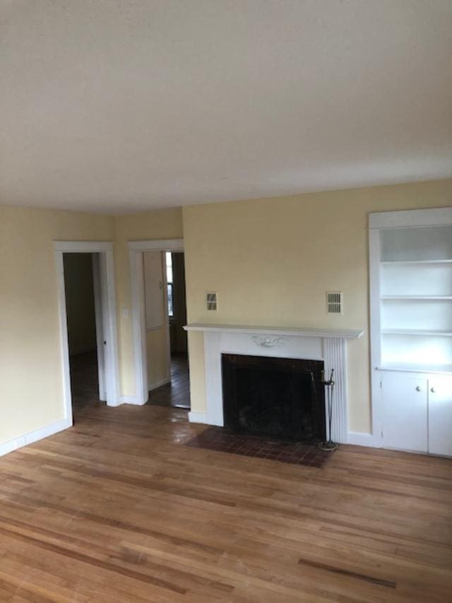 29 13th St, Bangor, ME 04401 - unfurnished living room with a fireplace with flush hearth, wood finished floors, baseboards, and built in features