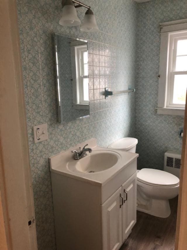 29 13th St, Bangor, ME 04401 - bathroom with vanity, wood finished floors, toilet, radiator, and wallpapered walls