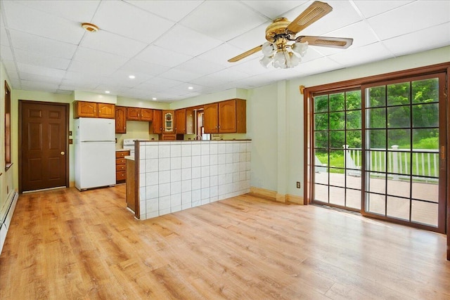 32 Skillings Corner Rd, Auburn, ME 04210 - kitchen featuring white appliances, a peninsula, ceiling fan, a drop ceiling, and light wood-style floors