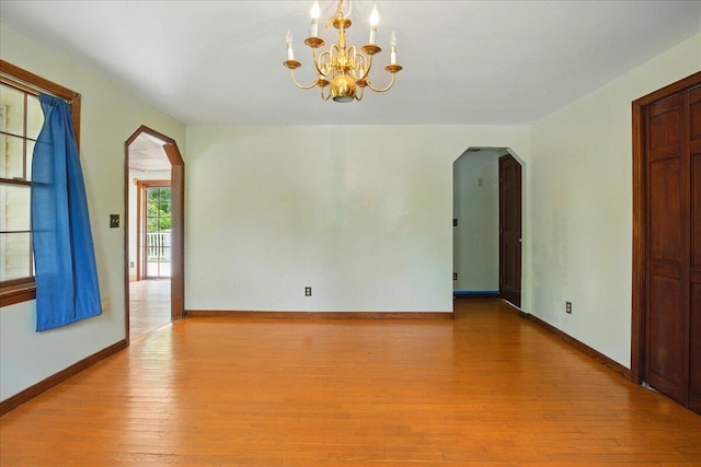 32 Skillings Corner Rd, Auburn, ME 04210 - spare room featuring arched walkways, wood-type flooring, a chandelier, and baseboards