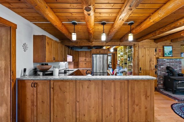 21 Jones Dr, Hartford, ME 04220 - kitchen featuring stainless steel refrigerator, brown cabinets, a wooden ceiling with exposed beams, light wood-type flooring, and a wood stove