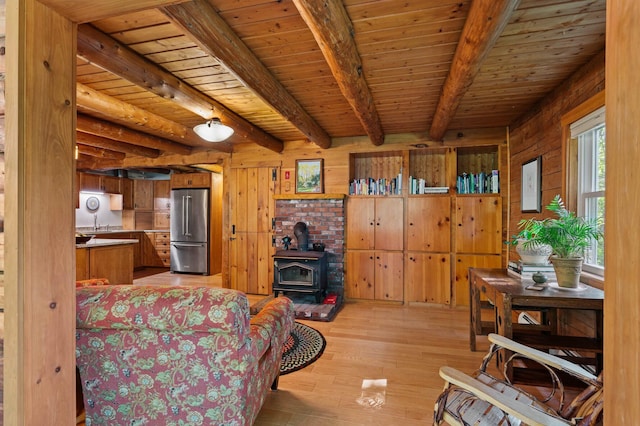 21 Jones Dr, Hartford, ME 04220 - living area featuring a wood stove, light wood finished floors, wooden walls, and a wooden ceiling with exposed beams