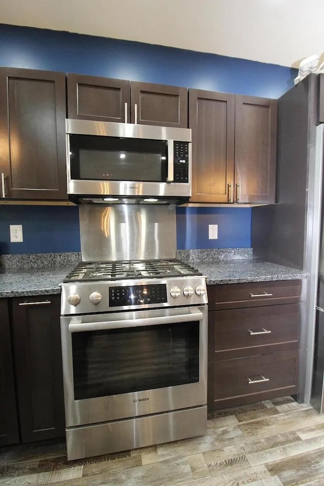 9 Springer Ln, Morrill, ME 04952 - kitchen featuring appliances with stainless steel finishes, dark brown cabinetry, light wood-type flooring, and light stone countertops