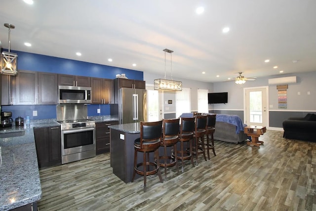 9 Springer Ln, Morrill, ME 04952 - kitchen featuring stainless steel appliances, a breakfast bar area, wood finished floors, a kitchen island, and light stone countertops