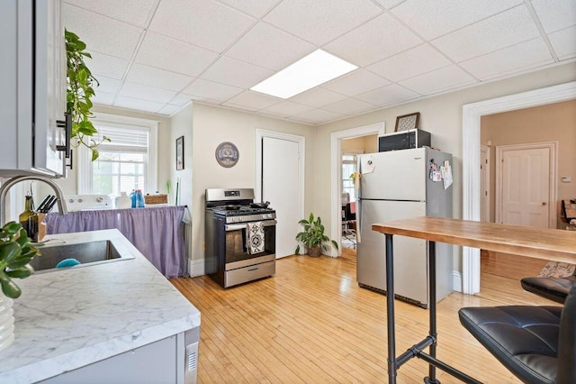 130 Emery St, Portland, ME 04102 - kitchen featuring stainless steel gas range, freestanding refrigerator, light countertops, light wood-type flooring, and a drop ceiling