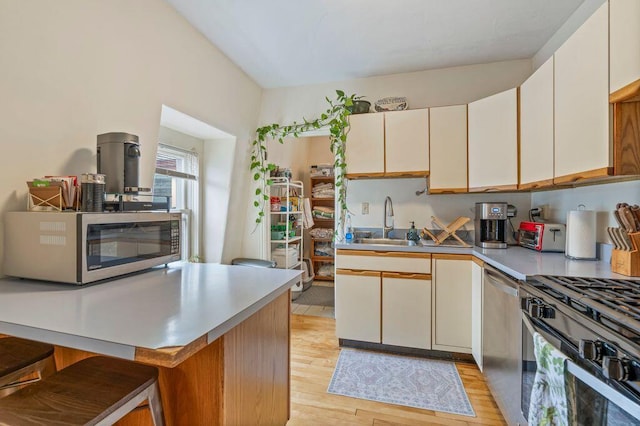 130 Emery St, Portland, ME 04102 - kitchen featuring stainless steel appliances, light wood-style flooring, a breakfast bar, light countertops, and white cabinetry