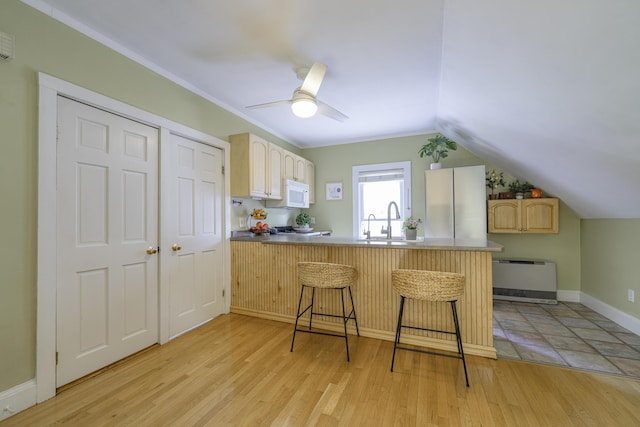 18 Sherman St Unit 4, Portland, ME 04101 - kitchen with white microwave, light brown cabinetry, a peninsula, a kitchen bar, and light wood-style floors