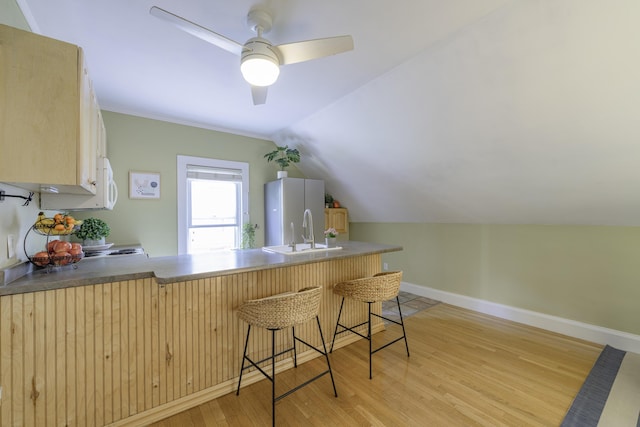 18 Sherman St Unit 4, Portland, ME 04101 - kitchen featuring light wood-style floors, a breakfast bar, white microwave, lofted ceiling, and light brown cabinetry