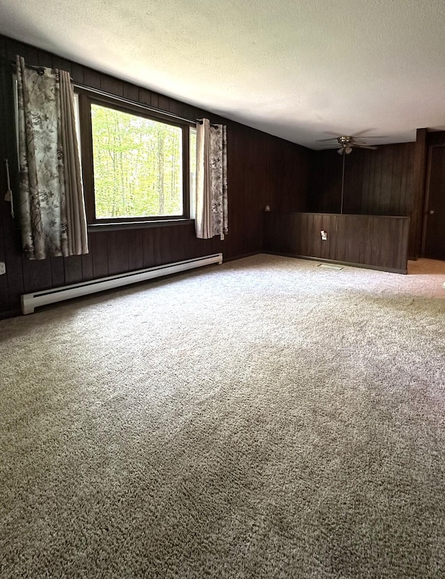 15 Balsam Ln, Naples, ME 04055 - spare room with baseboard heating, carpet, a textured ceiling, ceiling fan, and wood walls