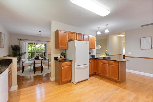 8 Kavanaugh Rd Unit 8, Old Orchard Beach, ME 04064 - kitchen with white appliances, light wood finished floors, brown cabinetry, a peninsula, and decorative light fixtures
