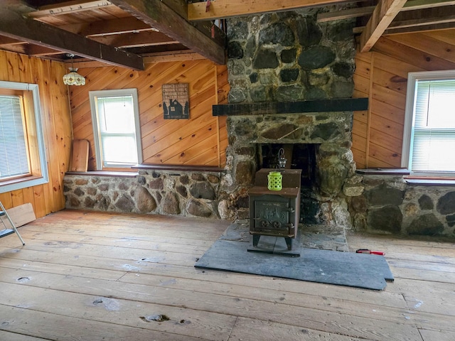 291 Pea Ridge Rd, Chester, ME 04457 - unfurnished living room with beamed ceiling, wood walls, plenty of natural light, hardwood / wood-style flooring, and a wood stove