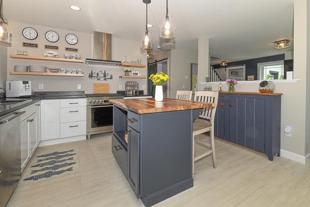 7 Elysian Way, Bridgton, ME 04009 - kitchen featuring open shelves, wall chimney exhaust hood, stainless steel appliances, butcher block countertops, and a kitchen breakfast bar