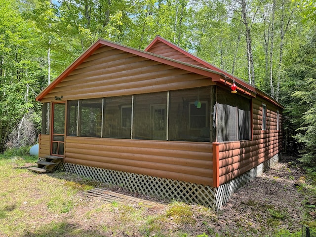 71 Wilderness Way, Burlington, ME 04417 - view of front facade with a sunroom, log veneer siding, a view of trees, and entry steps