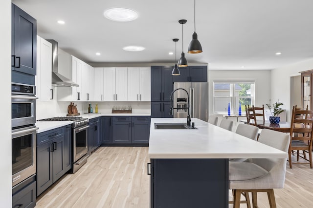 25 Royale Dr, Sidney, ME 04330 - kitchen with stainless steel appliances, a kitchen breakfast bar, light wood finished floors, a kitchen island with sink, and light countertops