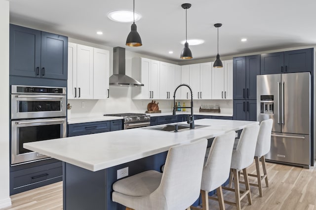 25 Royale Dr, Sidney, ME 04330 - kitchen with high end appliances, wall chimney exhaust hood, a sink, a breakfast bar, and light wood-style floors