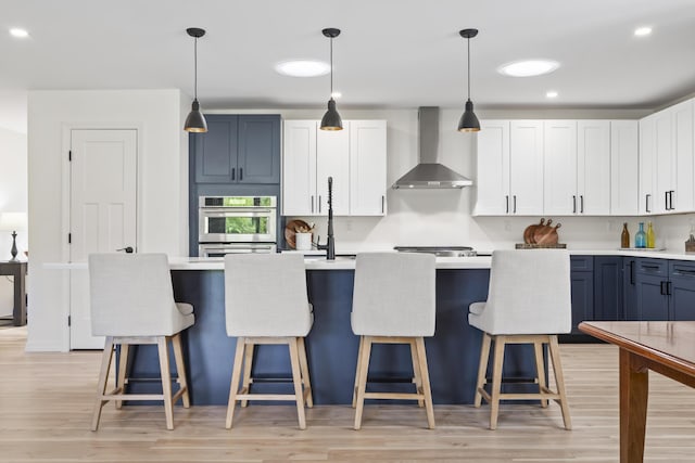 25 Royale Dr, Sidney, ME 04330 - kitchen featuring wall chimney range hood, light countertops, a kitchen bar, and recessed lighting