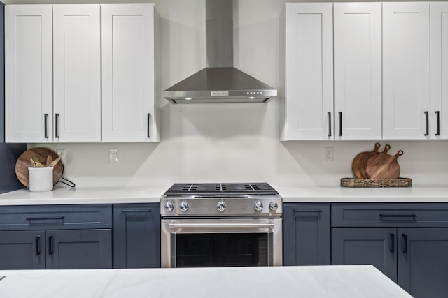 25 Royale Dr, Sidney, ME 04330 - kitchen with stainless steel gas range, wall chimney range hood, light countertops, and white cabinetry