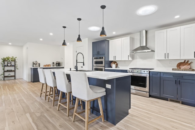 25 Royale Dr, Sidney, ME 04330 - kitchen with wall chimney exhaust hood, appliances with stainless steel finishes, light wood finished floors, a breakfast bar area, and light countertops