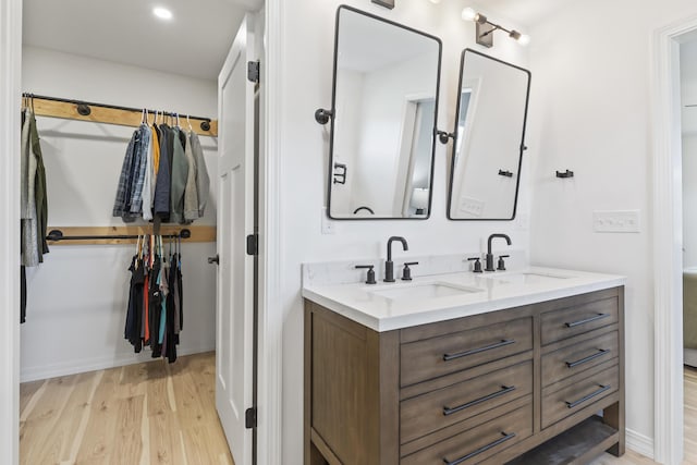 25 Royale Dr, Sidney, ME 04330 - bathroom featuring wood finished floors, double vanity, a spacious closet, and baseboards