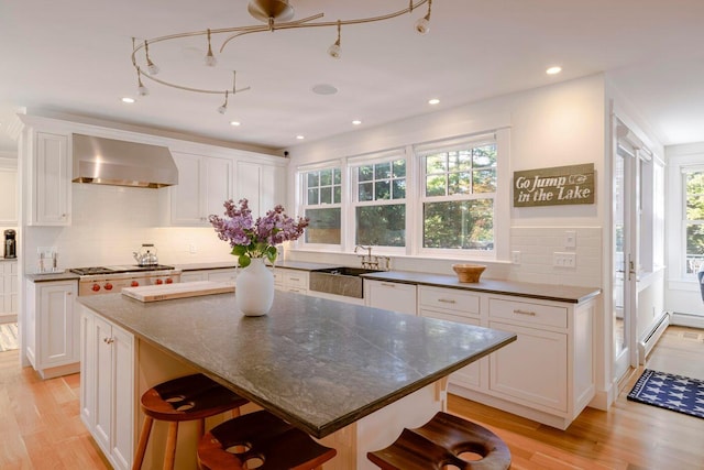 19 Vista Way, Mount Desert, ME 04660 - kitchen with wall chimney exhaust hood, a breakfast bar area, white cabinets, decorative backsplash, and recessed lighting