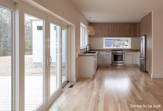 4 Windward Rdg, Biddeford, ME 04005 - kitchen featuring stainless steel appliances, light wood finished floors, pendant lighting, and white cabinets