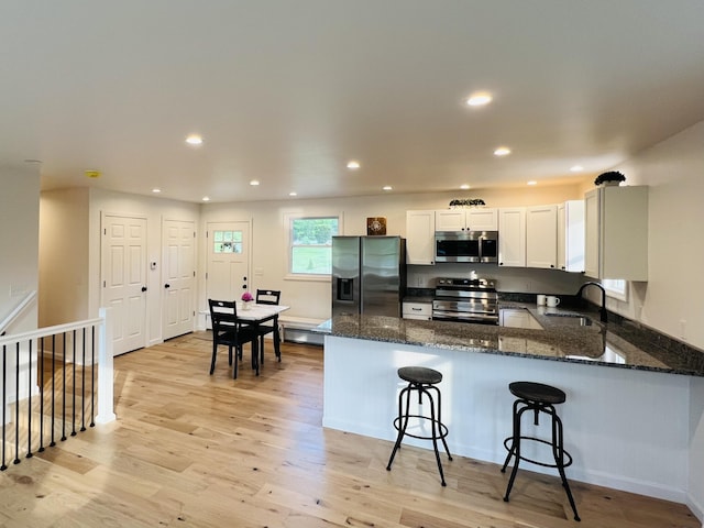 23 Ichabod Ln, Hampden, ME 04444 - kitchen with appliances with stainless steel finishes, dark stone counters, light wood-style floors, a peninsula, and recessed lighting