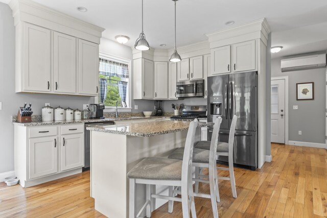 54 Tree Farm Rd, Brunswick, ME 04011 - kitchen with appliances with stainless steel finishes, a wall unit AC, light wood finished floors, light stone counters, and pendant lighting