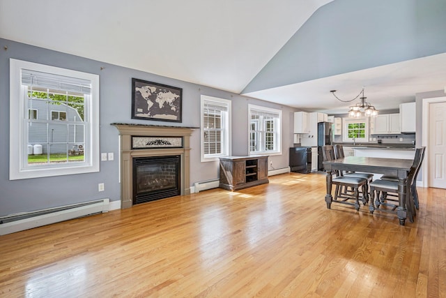 38 Shadagee Rd, Saco, ME 04072 - living room featuring baseboard heating, a glass covered fireplace, light wood-style floors, and vaulted ceiling