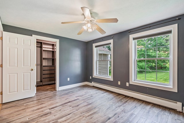 38 Shadagee Rd, Saco, ME 04072 - unfurnished bedroom featuring a baseboard heating unit, light wood-style flooring, baseboards, a spacious closet, and ceiling fan