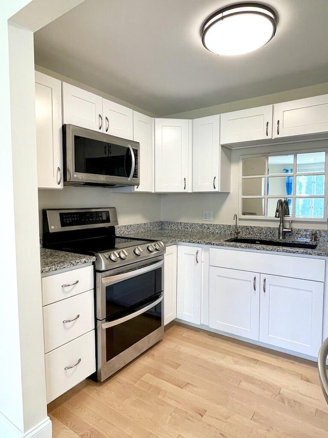 101-2 Waldo Ave Unit 3, Belfast, ME 04915 - kitchen featuring appliances with stainless steel finishes, a sink, light wood-type flooring, stone countertops, and white cabinets