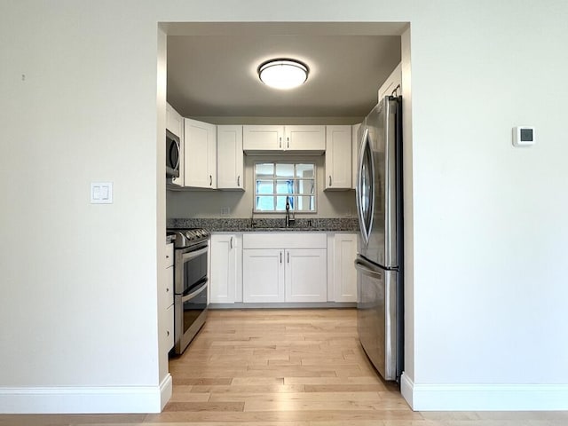 101-2 Waldo Ave Unit 3, Belfast, ME 04915 - kitchen with appliances with stainless steel finishes, white cabinets, light wood-type flooring, and baseboards