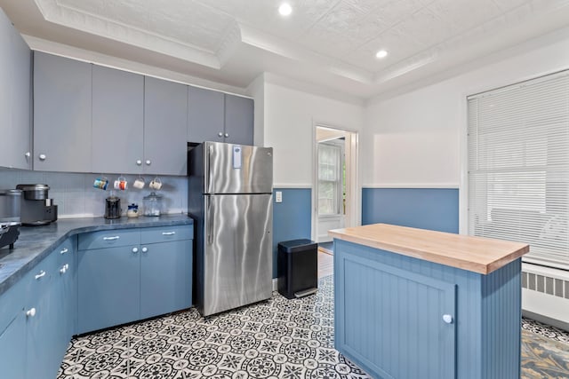10 Hollingsworth St, Winslow, ME 04901 - kitchen with freestanding refrigerator, a raised ceiling, wood counters, radiator, and blue cabinets