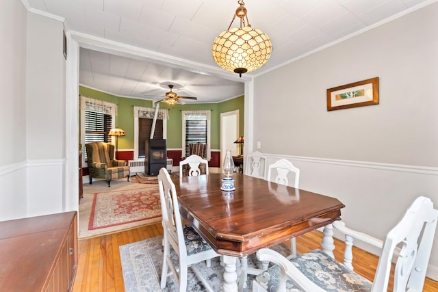 10 Hollingsworth St, Winslow, ME 04901 - dining space featuring a wood stove, light wood finished floors, ornamental molding, radiator, and a ceiling fan